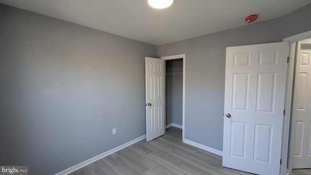 unfurnished bedroom with a closet, light wood-style floors, and baseboards