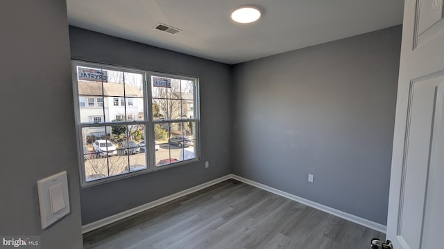 unfurnished room featuring visible vents, baseboards, and wood finished floors