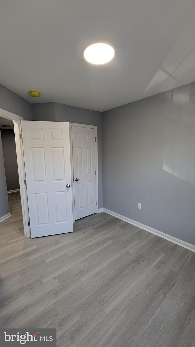 unfurnished bedroom with a closet, baseboards, and wood finished floors