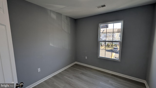 unfurnished room with visible vents, baseboards, and wood finished floors