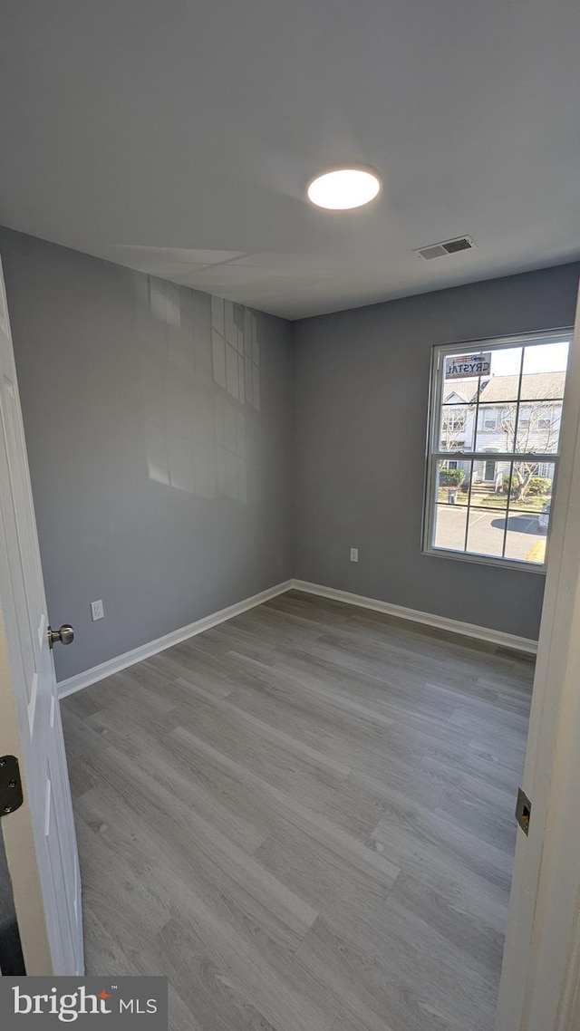 empty room with visible vents, baseboards, and wood finished floors