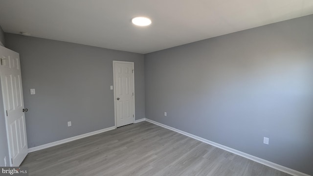 empty room with light wood-style flooring and baseboards