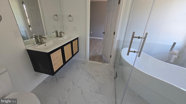 full bathroom with a freestanding bath, toilet, marble finish floor, and a sink