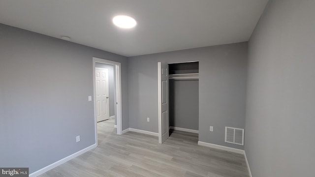 unfurnished bedroom with a closet, visible vents, light wood-type flooring, and baseboards