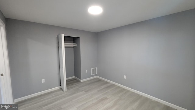 unfurnished bedroom featuring light wood finished floors, visible vents, a closet, and baseboards