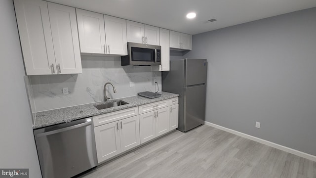 kitchen with visible vents, backsplash, white cabinets, stainless steel appliances, and a sink