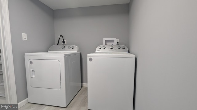 washroom featuring washer and clothes dryer, laundry area, baseboards, and light wood-style floors