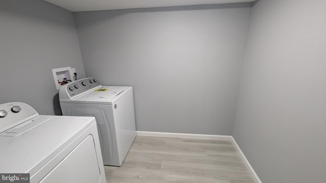 laundry room featuring laundry area, light wood-style flooring, separate washer and dryer, and baseboards