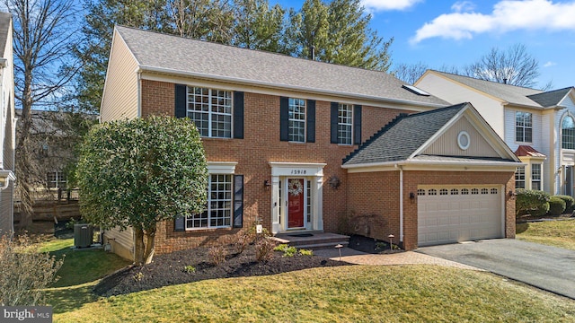 view of front facade with cooling unit, driveway, a shingled roof, a garage, and brick siding