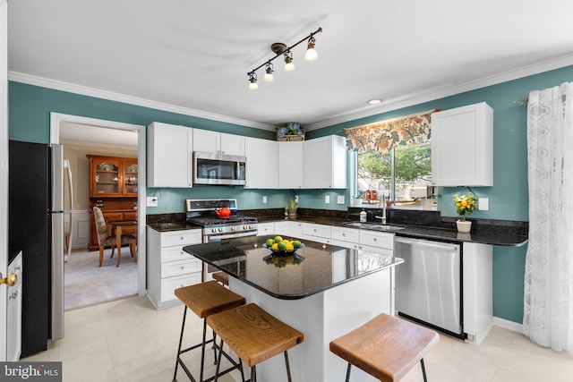 kitchen featuring white cabinetry, ornamental molding, appliances with stainless steel finishes, and a sink