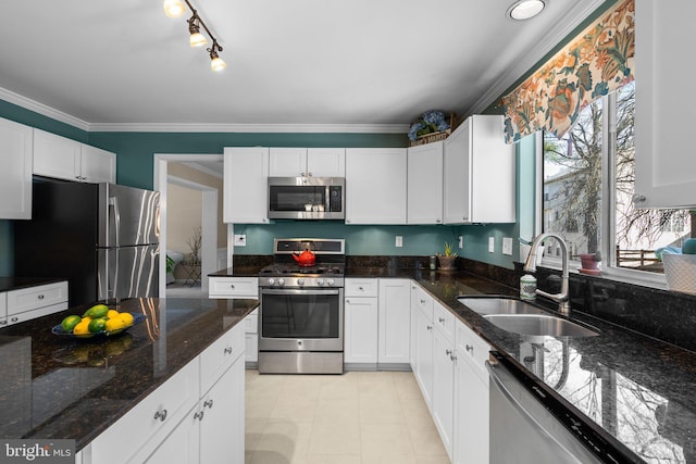 kitchen featuring a sink, stainless steel appliances, dark stone counters, white cabinets, and crown molding