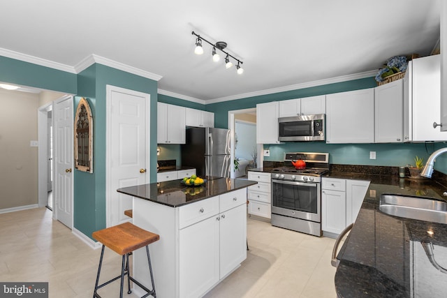 kitchen with appliances with stainless steel finishes, white cabinetry, crown molding, and a sink