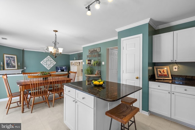 kitchen featuring white cabinets, a center island, and crown molding