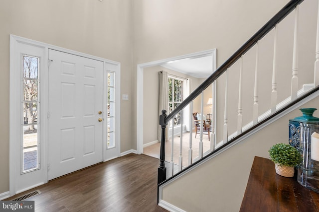 foyer featuring stairway, baseboards, visible vents, and dark wood-style flooring