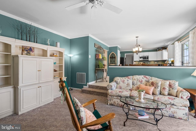 living area with visible vents, baseboards, ornamental molding, light carpet, and ceiling fan with notable chandelier