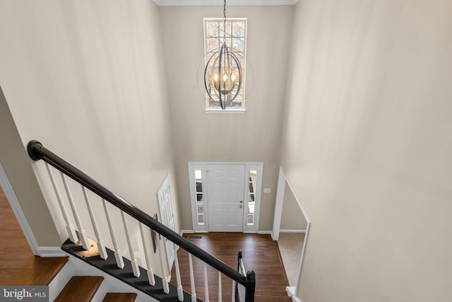 entrance foyer featuring wood finished floors, stairway, a high ceiling, an inviting chandelier, and baseboards