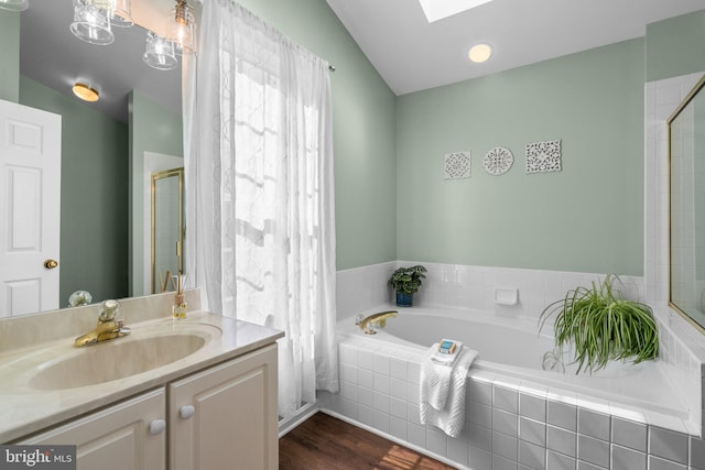 bathroom with a shower with shower door, a skylight, wood finished floors, a bath, and vanity