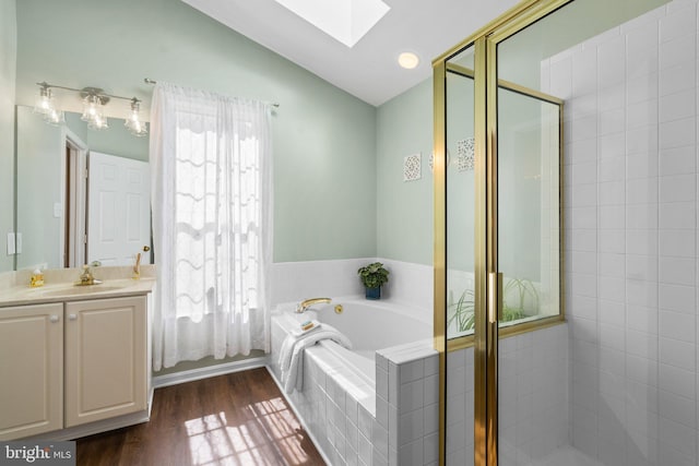 full bathroom featuring a garden tub, vaulted ceiling with skylight, a stall shower, wood finished floors, and vanity