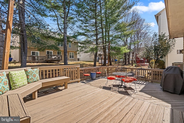 wooden terrace with outdoor dining area and a grill