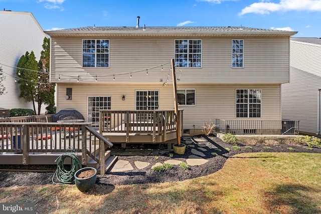 rear view of house featuring a wooden deck and a lawn