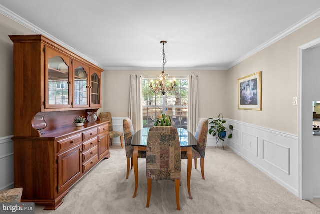 dining space with a wainscoted wall, ornamental molding, a decorative wall, light colored carpet, and a chandelier