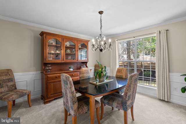 dining area featuring crown molding, light colored carpet, and wainscoting