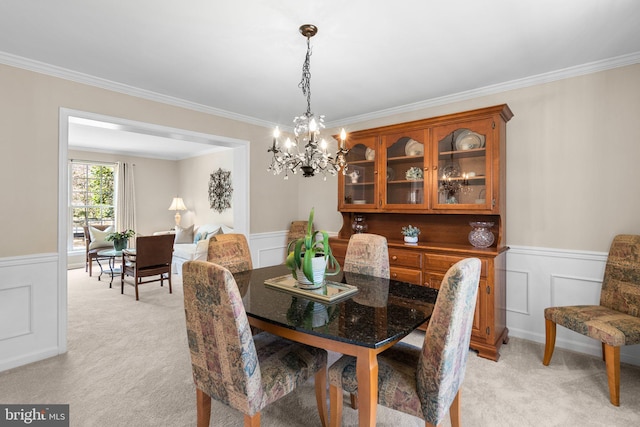 dining space featuring light colored carpet, a chandelier, and wainscoting