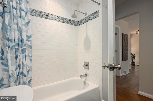 bathroom featuring visible vents, baseboards, toilet, shower / bath combo with shower curtain, and wood finished floors