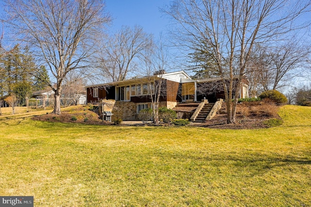 back of property with a lawn and stairs