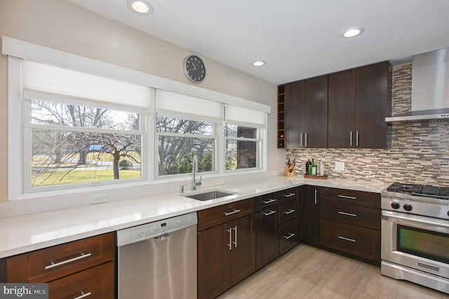 kitchen featuring tasteful backsplash, plenty of natural light, stainless steel appliances, wall chimney exhaust hood, and a sink