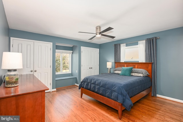 bedroom with light wood-style flooring, baseboards, two closets, and ceiling fan