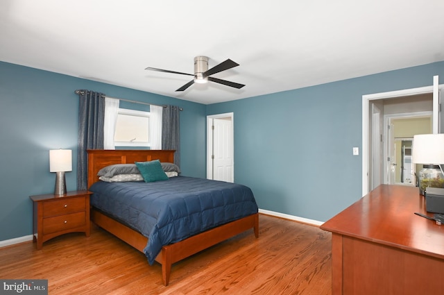 bedroom featuring baseboards, light wood-style floors, and a ceiling fan