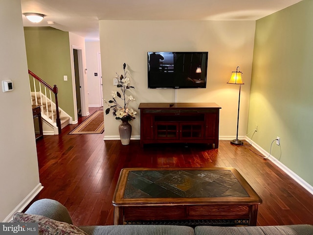 living area featuring baseboards, wood-type flooring, and stairs