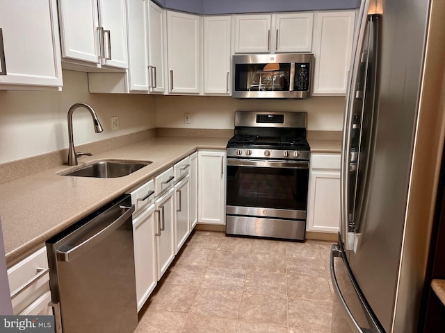 kitchen with a sink, stainless steel appliances, white cabinets, and light countertops