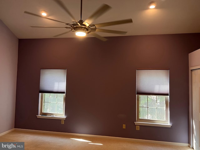 spare room featuring a wealth of natural light, baseboards, light carpet, and ceiling fan