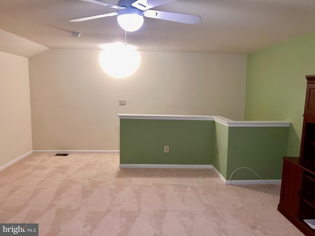 carpeted empty room with visible vents, baseboards, ceiling fan, and vaulted ceiling