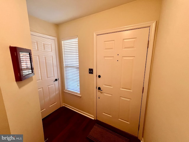 foyer entrance with dark wood-style floors and baseboards