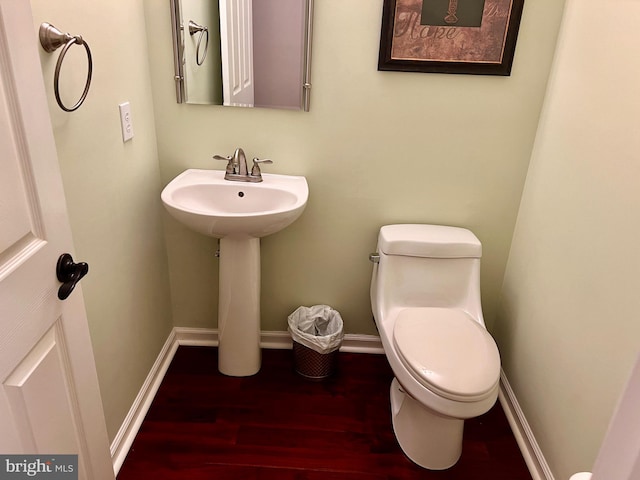 bathroom with a sink, toilet, baseboards, and wood finished floors