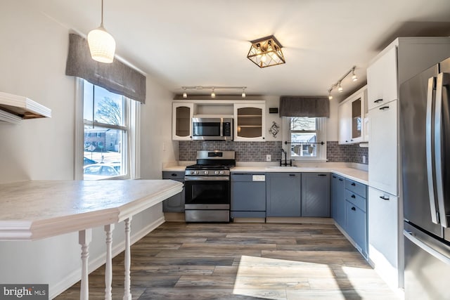 kitchen featuring dark wood finished floors, light countertops, backsplash, and appliances with stainless steel finishes