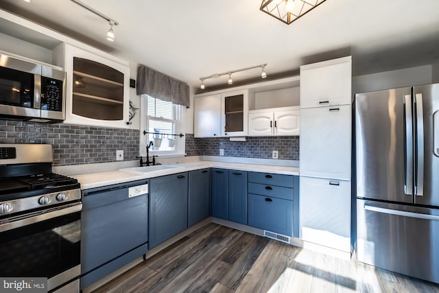 kitchen with stainless steel appliances, glass insert cabinets, light countertops, and a sink