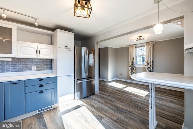 kitchen featuring wood finished floors, visible vents, freestanding refrigerator, decorative backsplash, and light countertops