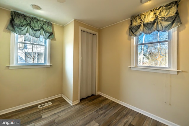 unfurnished bedroom featuring a closet, baseboards, visible vents, and dark wood-style flooring