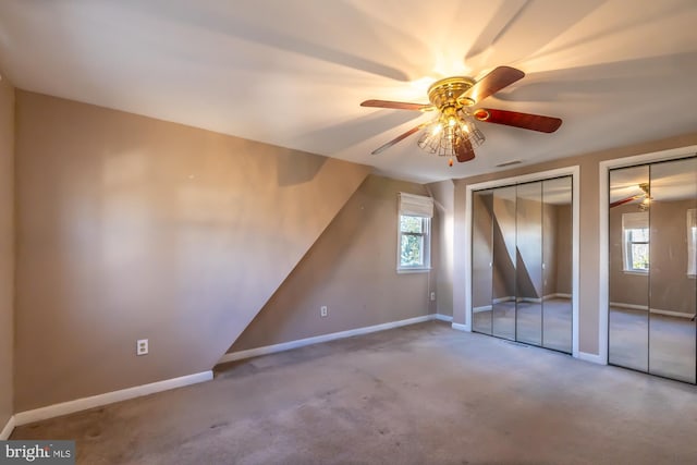 unfurnished bedroom with a ceiling fan, visible vents, baseboards, carpet floors, and two closets