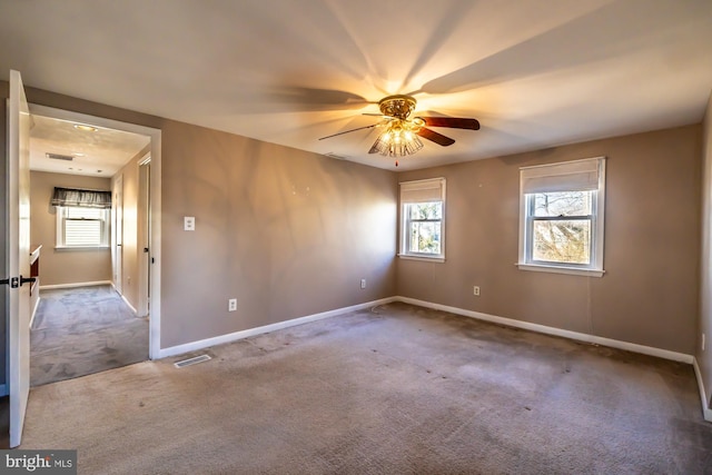 empty room with visible vents, carpet flooring, a ceiling fan, and baseboards