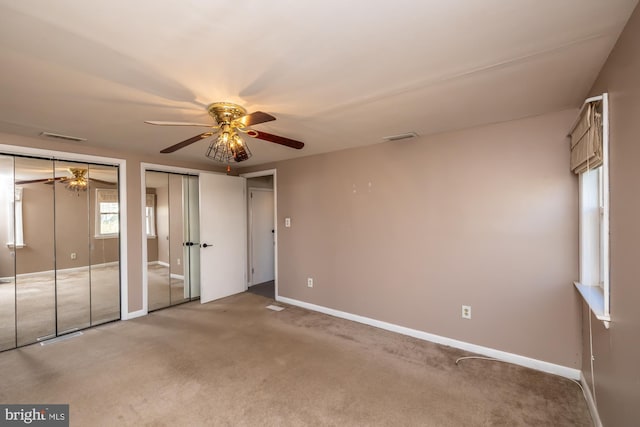 unfurnished bedroom with baseboards, visible vents, two closets, and carpet