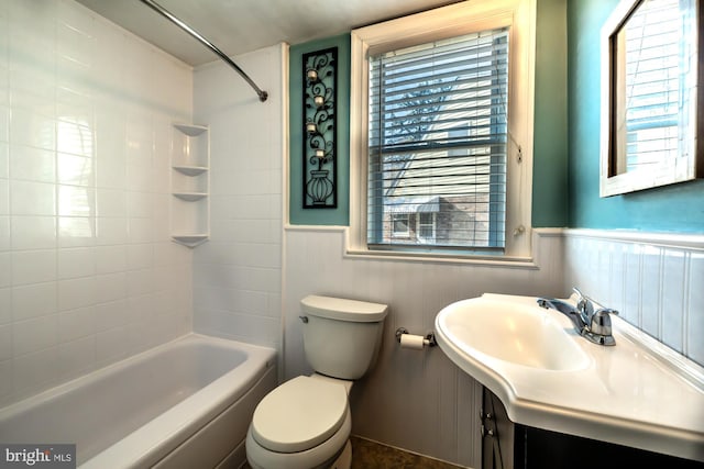 bathroom with bathing tub / shower combination, vanity, toilet, and wainscoting