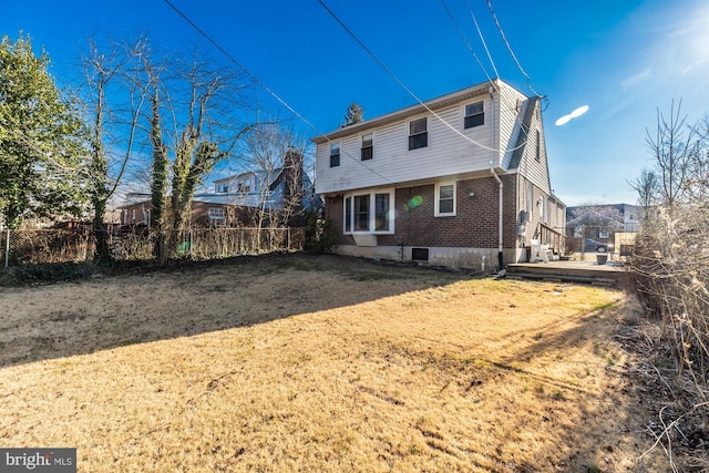 back of house featuring brick siding and fence