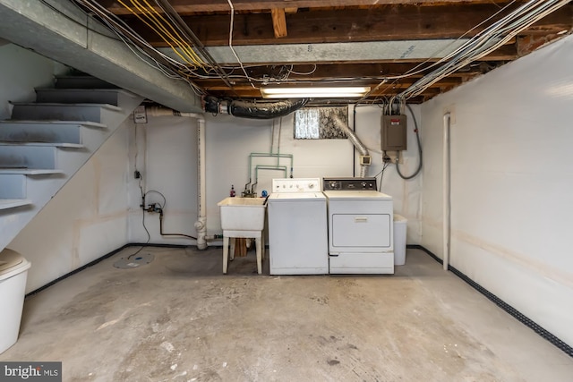 basement with washing machine and clothes dryer, stairs, electric panel, and a sink