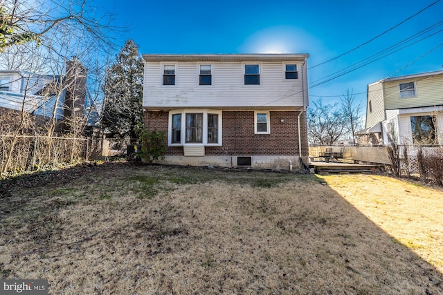 back of house with a yard, fence, and brick siding