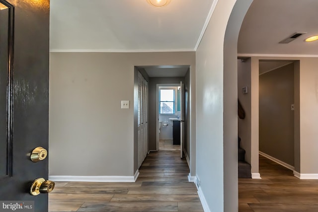 corridor featuring ornamental molding, visible vents, arched walkways, and baseboards